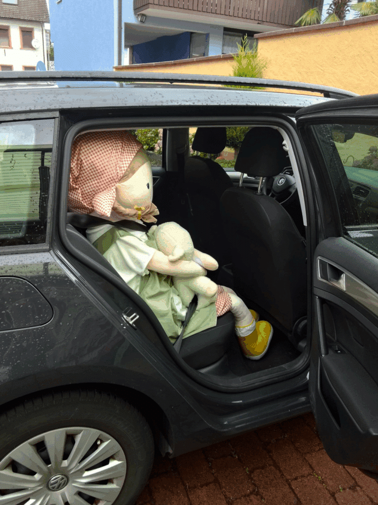 Puppe Lotta sitzt angeschnallt im Auto.